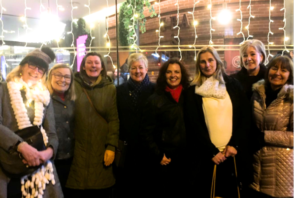 Group of Culture Calendar women smiling and laughing outside a theatre in Liverpool on a festive winter night, after enjoying a live comedy show.