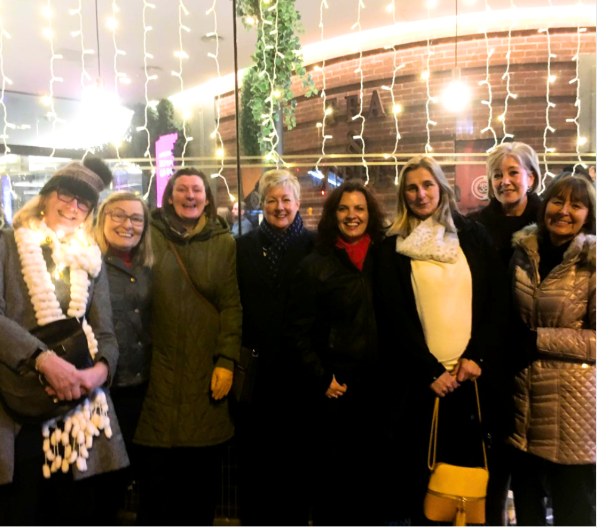 Group of Culture Calendar women smiling and laughing outside a theatre in Liverpool on a festive winter night, after enjoying a live comedy show.