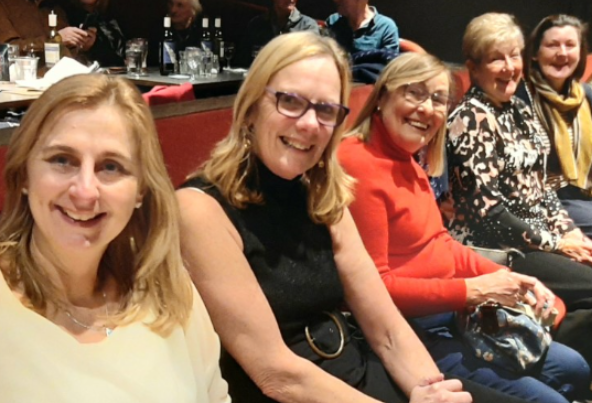 Smiling women enjoying theatre interval together at a live performance in Merseyside, part of Culture Calendar Women’s Social Group for arts, culture, and friendship over 40