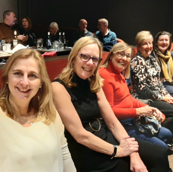 Smiling women enjoying theatre interval together at a live performance in Merseyside, part of Culture Calendar Women’s Social Group for arts, culture, and friendship over 40