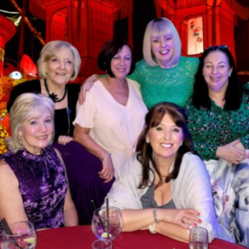 Group of smiling Culture Calendar women enjoying a Chinese New Year banquet celebration in Ormskirk, surrounded by festive decor and laughter.