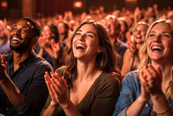 Audience members smiling and applauding during a live theatre performance, capturing the joy of a shared experience
